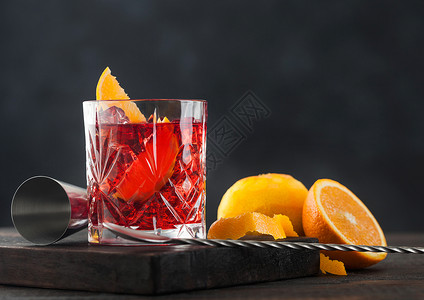 酒勺晶杯中的白葡萄鸡尾酒橙片砍板上新鲜的生橙子木本底有勺背景