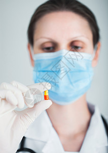 蓝色面罩和清晰的乳胶手套医生持有灰色院墙底的药片抗生素和治疗药片图片
