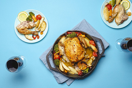 鸡肉加蔬菜和两杯红酒鸡蔬菜用铁铸烤鸡和蔬菜加蓝盘图片