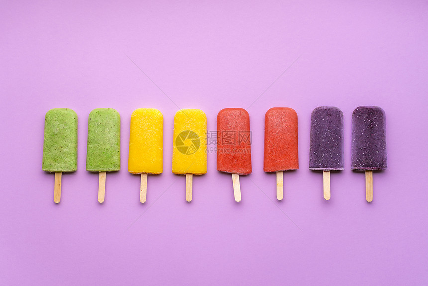 紫色背景的水果冰淇淋系列平躺着彩虹冰淇淋贴在棍子上夏季新鲜甜点素食软糖图片