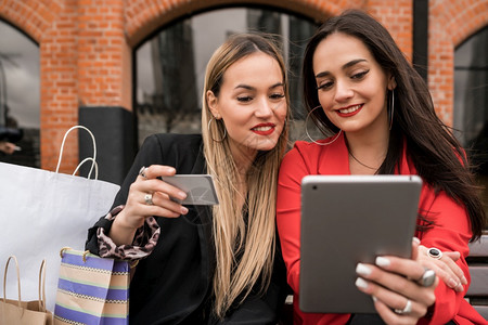 女人用信卡和平板电脑在户外购物图片