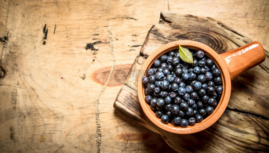新鲜蓝莓放在杯子上木制桌子上图片