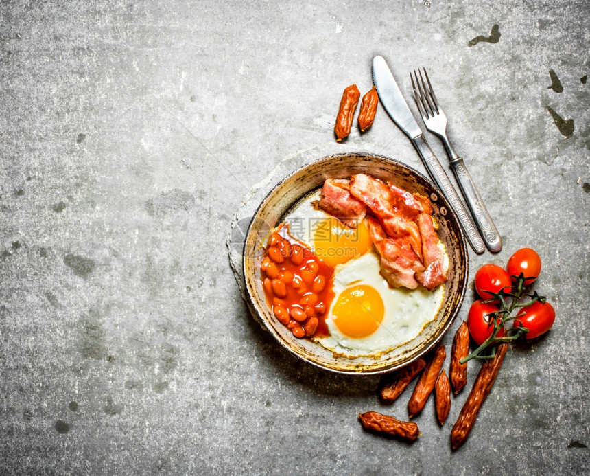早上餐培根炸鸡蛋豆子和橙汁在石桌上图片