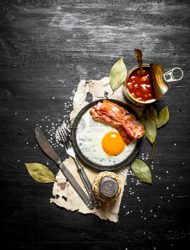 早餐豆酱加煎蛋和培根黑木背景图片