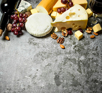 一块奶酪红酒和坚果在石板上图片