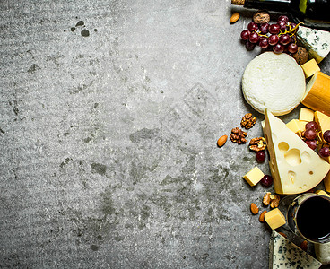 一块奶酪红酒和坚果在石板上图片
