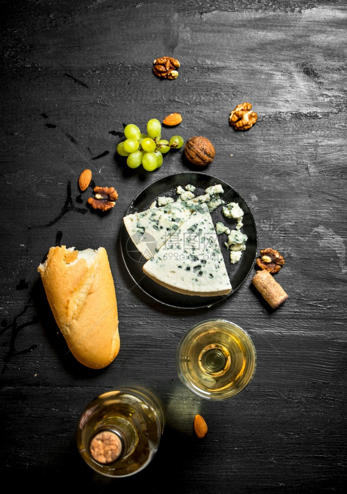 白葡萄酒加法国蓝奶酪和坚果黑木板上图片