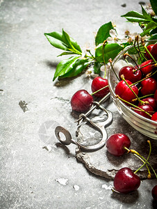 杯子上的红樱桃和金属工具石头桌上的红樱桃图片