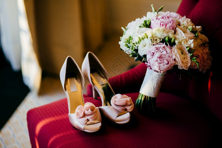 红椅子上的鲜花婚礼准备配件粉红新娘的鞋子和房间的红花束图片