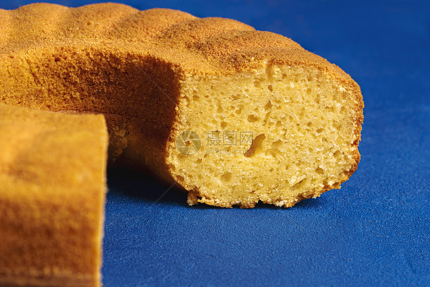 蓝背景的切片玉米面蛋糕以做的海绵蛋糕图片