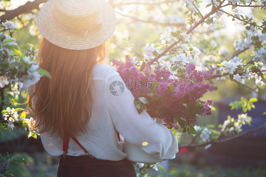 夏天穿着帽子和吊带的漂亮女孩在花园的里带一束图片