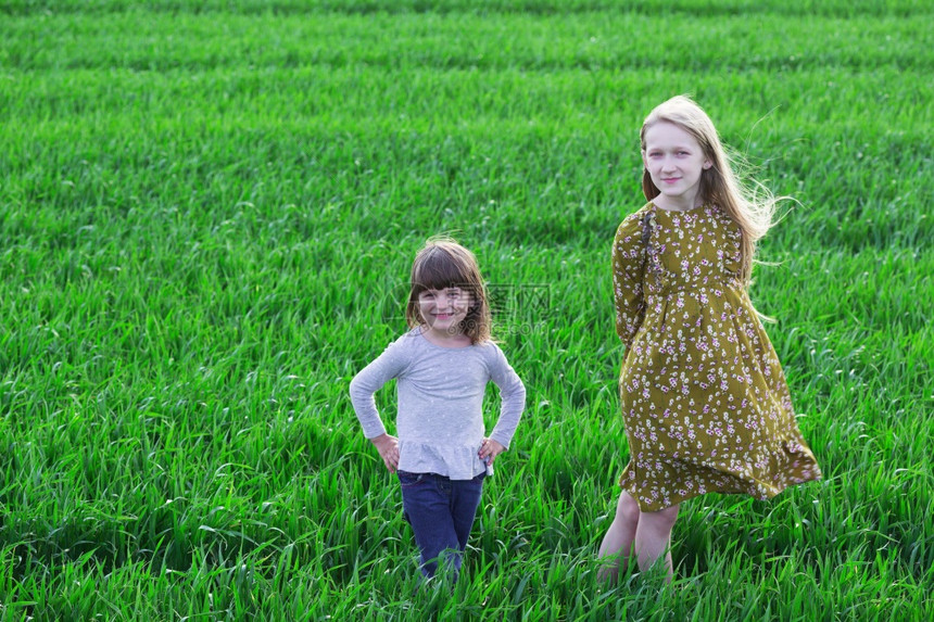 姐妹俩在绿色的草地里图片