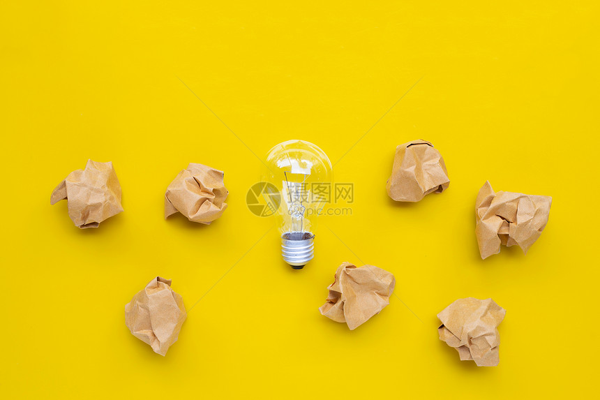 黄色背景的棕折面纸球灯泡顶部视图图片
