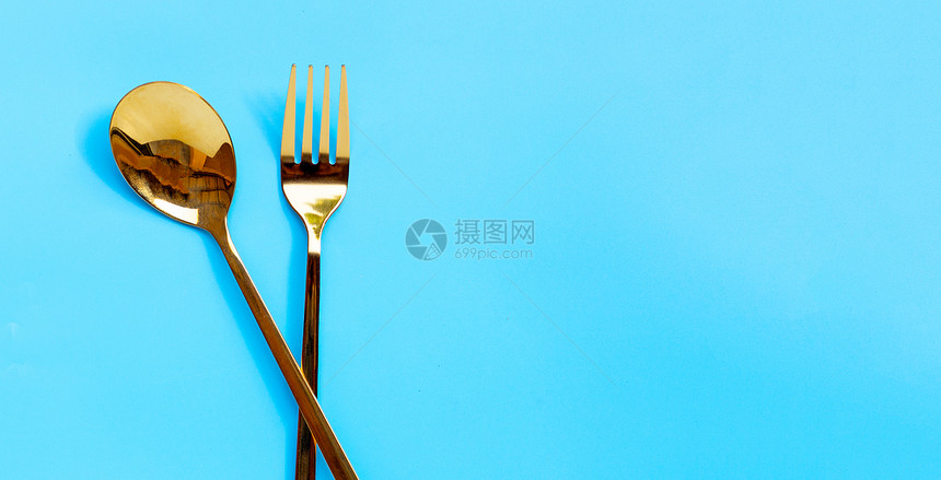 金勺和蓝背景的叉子复制空间图片
