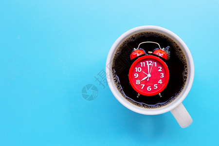 蓝色背景的咖啡杯中红色闹钟复制空间图片