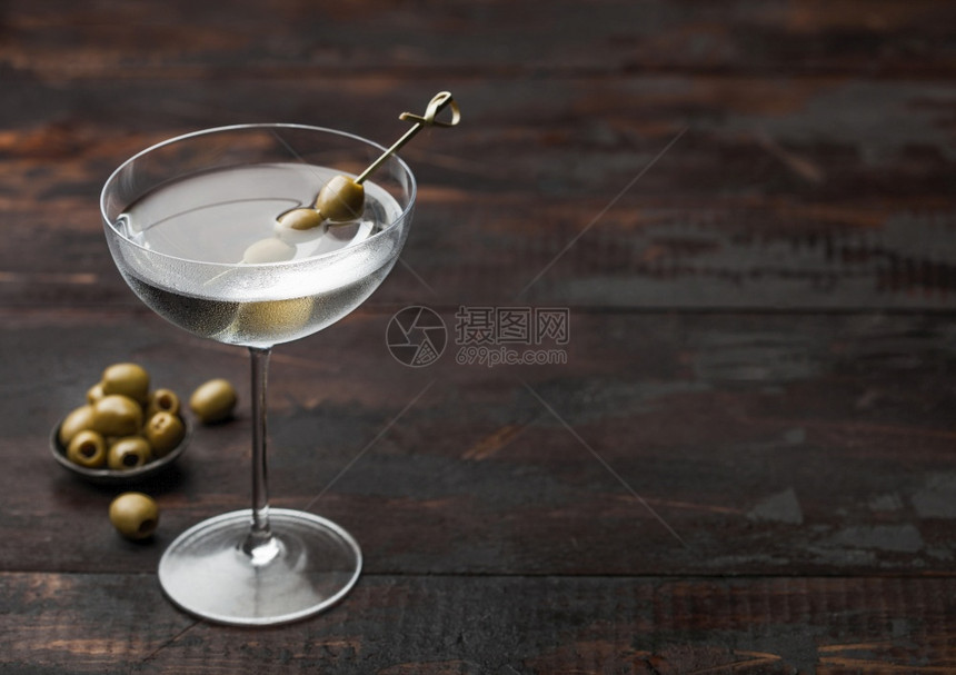 现代杯子里的伏特加马提尼酒鸡尾加橄榄金属碗里有橄榄黑木本底有竹棒图片