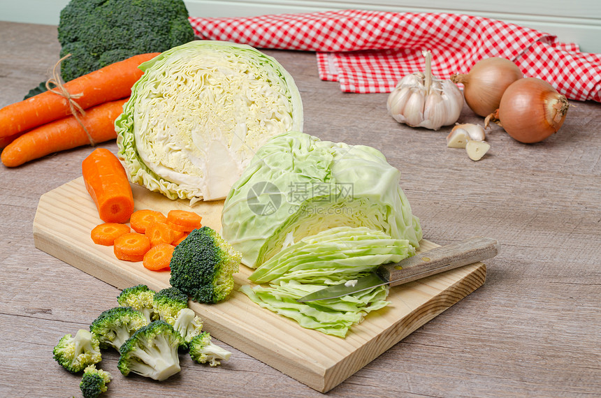 新鲜绿色花椰菜胡萝卜大蒜洋葱和木制切板的卷心菜图片