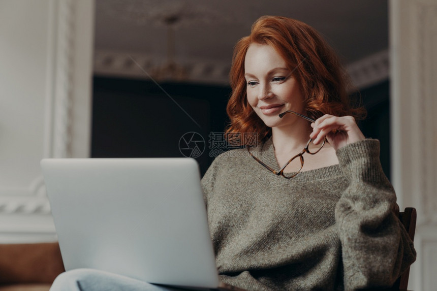 金发美女坐在沙发上玩电脑图片