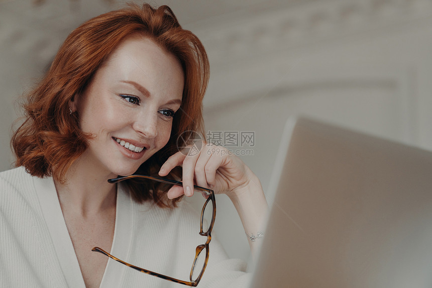 女网络设计师在笔记本电脑上使用应程序来创建项目工作进行在线研究和浏览互联网持有眼镜快乐的表达方式图片
