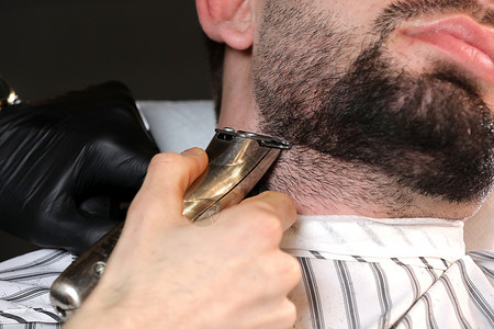理发师专业主在店剃胡子师专业大在店刮客户和师的胡子用电动剪辑机刮胡须理发师男子广告和理发店概念选择焦点剪裁人和理发师在店刮胡须专背景图片