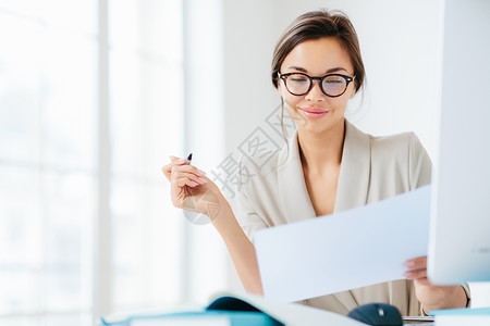 在纸质研究合同条款持笔写文件穿成正规在桌面上与白色宽敞的内地对面摆布图片