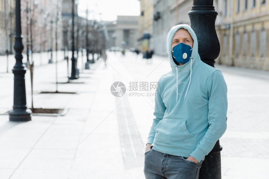 身穿运动衫和牛仔裤戴呼吸口罩以防止或感染在隔离期间走过空旷的城市街道图片