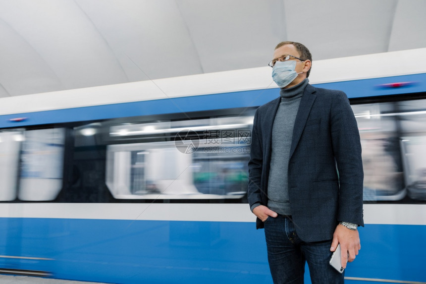 商人佩戴外科消毒面具以防止呼吸道疾病蔓延对地下列车造成威胁乘坐公共交通工具旅行手持智能机图片