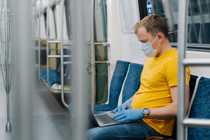 年轻人戴呼吸面具以防止冠状在笔记本电脑上自由职业在地铁运输中制造害怕生病在公共交通中旅行2019ncov图片
