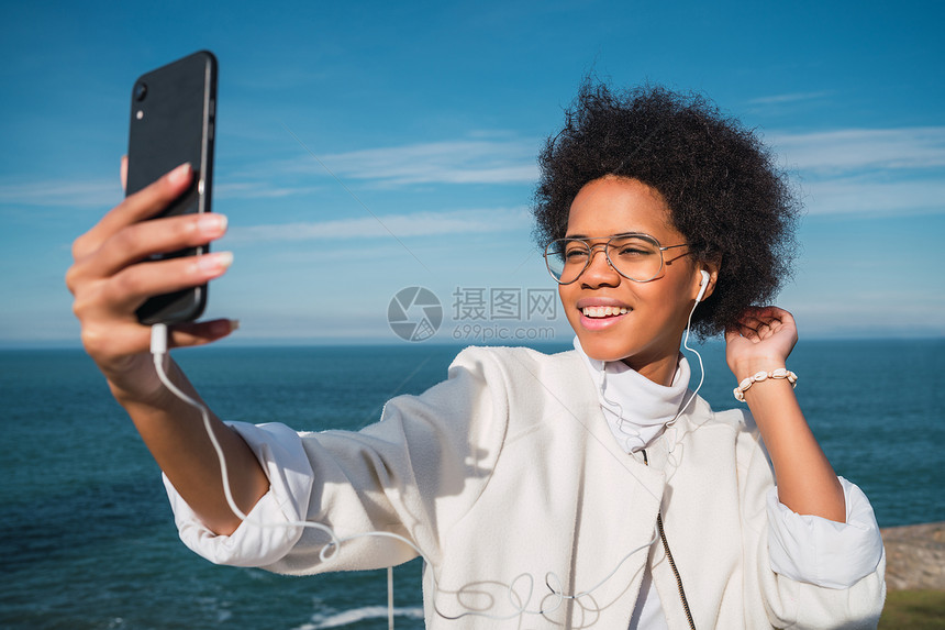 年轻美丽的拉丁女人用手机拍自的肖像图片