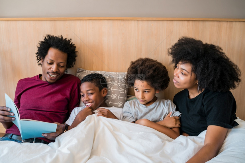 非洲家庭在里卧室的床上看书快乐肖像生活方式和家庭概念图片