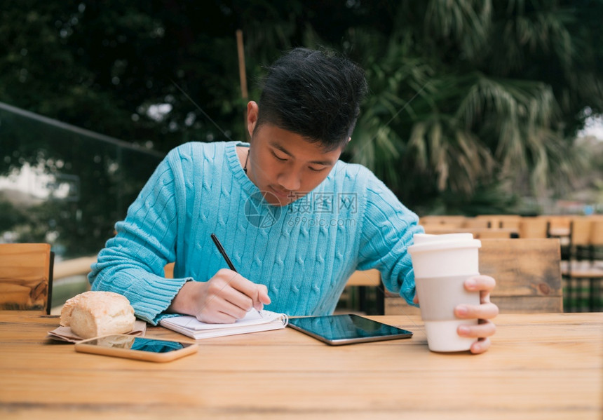 以数字平板电脑和笔记学习的年轻亚洲人肖像图片