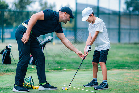 高尔夫球课教练和年轻男孩在高尔夫车场上图片