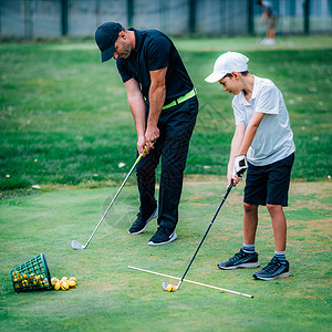 一个高尔夫教练和一个男孩在高尔夫练习场上图片