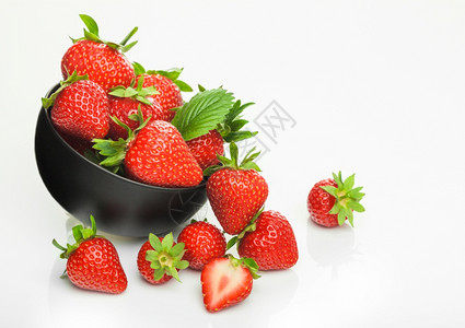 黑色陶瓷碗盘中的新鲜生有机草莓白色背景边有浆果顶部视图图片