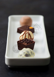 在白色瓷板上选择的奢华巧克力糖果黑底白和牛奶巧克力类图片