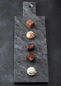 黑色marbel板上选择的奢华巧克力糖果白色黑牛奶巧克力顶部视图图片