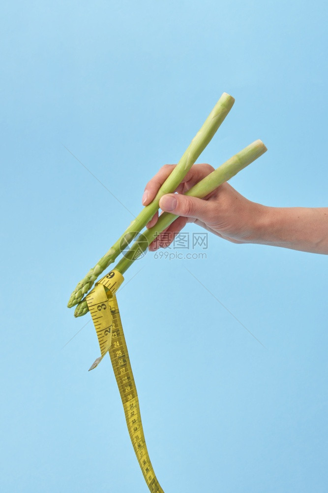 女和人的食物女和手拿着黄色的测量胶带作为面条对抗蓝色背景复制空间黄色的测量胶带作为日本或食物女和手和阿斯帕古棒正在使用测量胶带图片