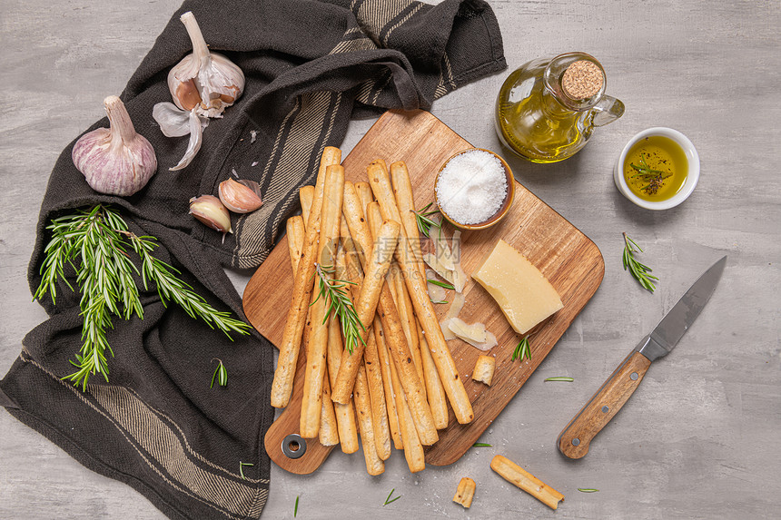 灰色背景的意大利传统面包棒加迷迭香干酪奶橄榄油大蒜和盐图片