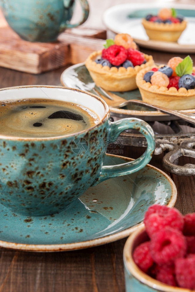 黑咖啡在蓝色的古年杯子和水果边上夹着草莓和蓝图片