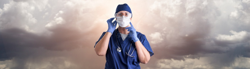 医生或护士在不祥云层上佩戴个人防护设备调整医疗面罩图片