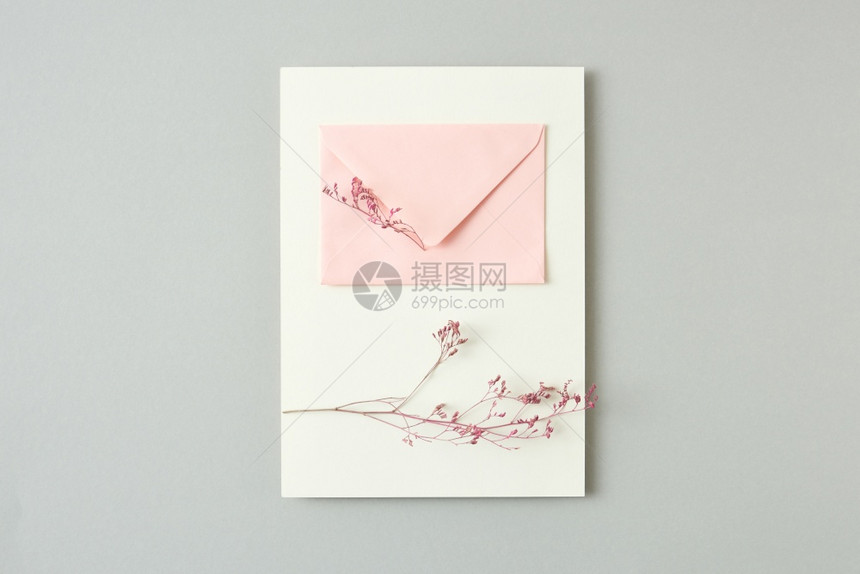 赠送鲜花和粉红纸信封在浅灰背景复制空间平地花朵树枝的假日卡片和浅灰背景的纸信封图片