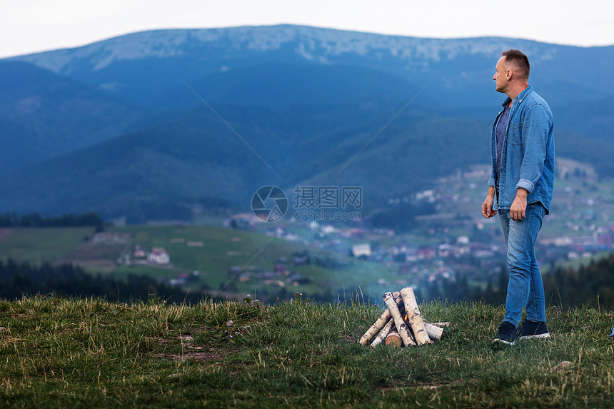 年轻男子站在山顶的夜空下燃烧着的火焰中活跃生方式概念活跃的生方式概念图片