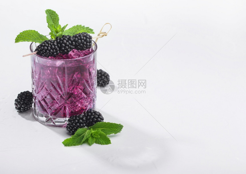 以黑莓冰和薄荷的清凉夏日鸡尾酒白色背景的苏打汽水和酒精混合深影的硬光图片