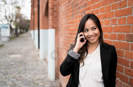 年轻拉丁女人在街上户外电话交谈的肖像城市概念图片