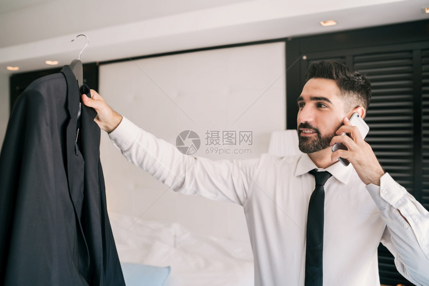 年轻商人在酒店房间的电话交谈肖像商业旅行概念图片