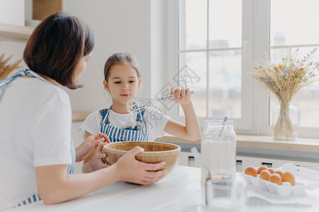 可爱女儿和妈妈一起做饭享受家庭气氛图片