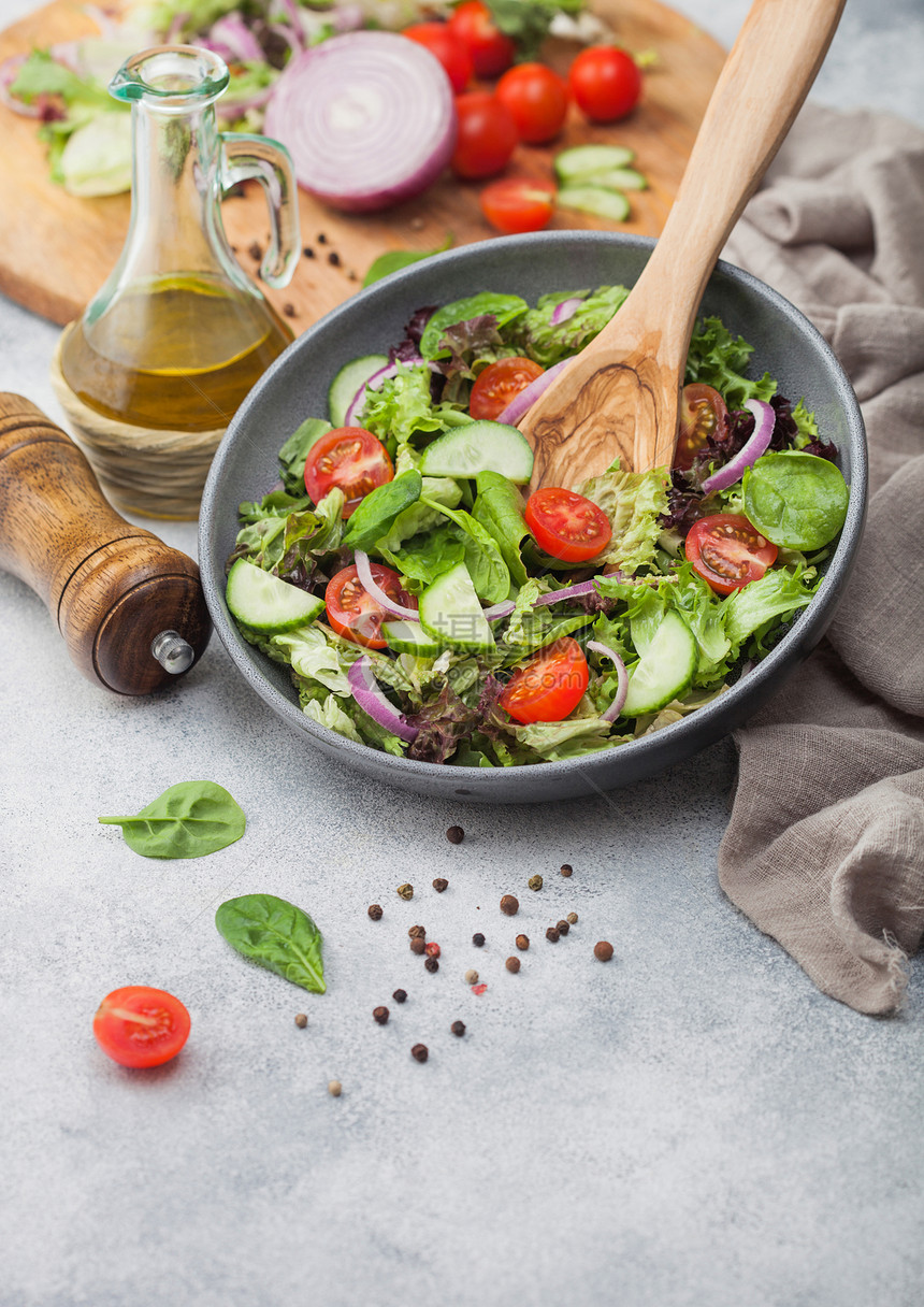 灰色一碗健康的新鲜素食蔬菜沙拉配有西红柿和黄瓜生菜菠底浅含橄榄油磨粉和切菜板上的新鲜蔬图片