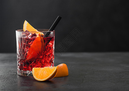 白葡萄鸡尾酒在晶玻璃里橙片和黑桌底的稻图片