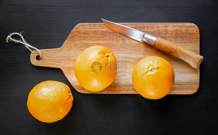橘子和旧的传统小刀放在木制的砧板上在砧板上放着橘子和传统的小刀图片