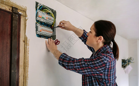 女电工在一所房子的配电板上工作电工正在修理房屋的配电板图片